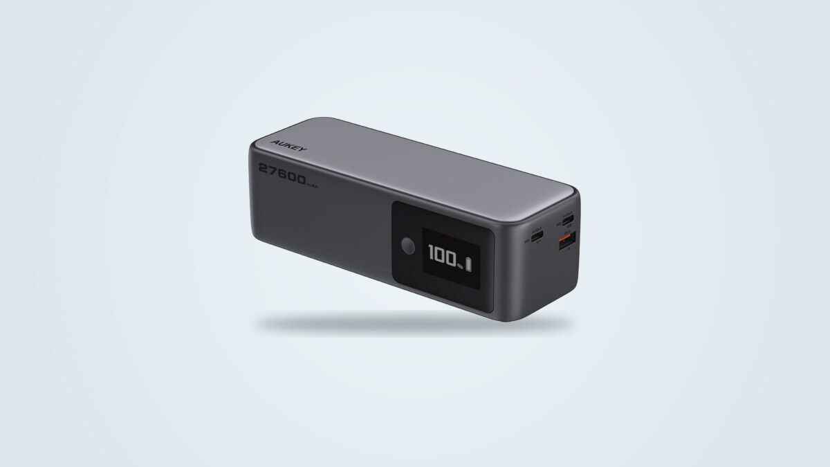 Aukey PB-Y63 Spark Sling power bank shown at a three-quarter angle, digital screen lit showing 100%, USB-C and USB-A ports visible on the end