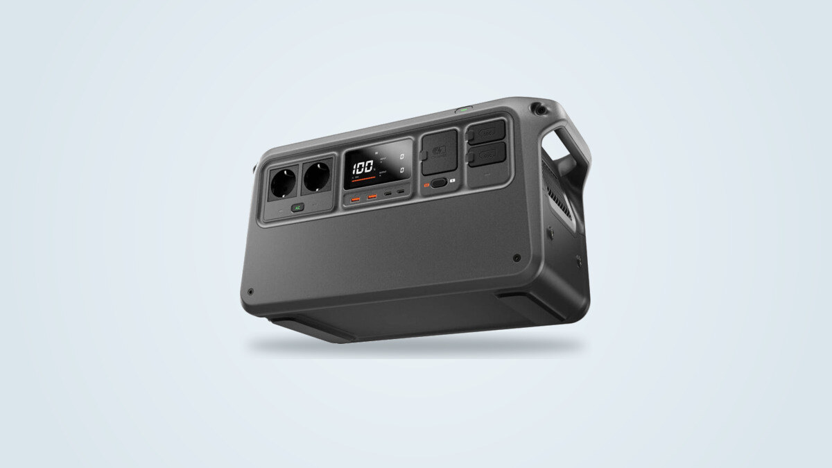 DJI Power 1000 V2 portable power station at a three-quarter angle, screen lit showing 100%, SDC ports and folding handle visible