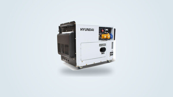 Generador diésel Hyundai DHY6000SE blanco y negro sobre chasis con ruedas, visto de tres cuartos, panel de enchufes 230 V y pantalla digital visibles