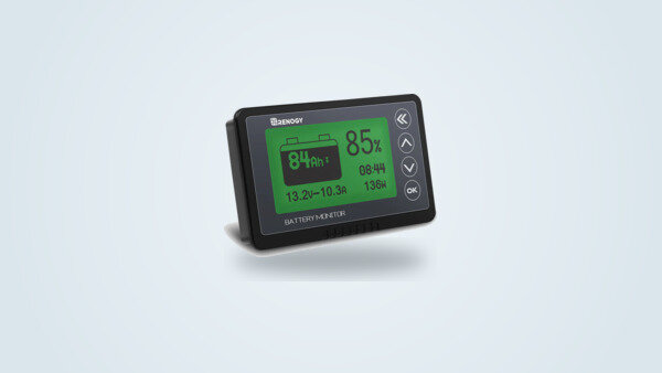 Renogy RBM500 battery monitor at a three-quarter angle, backlit LCD screen showing voltage, current and charge percentage