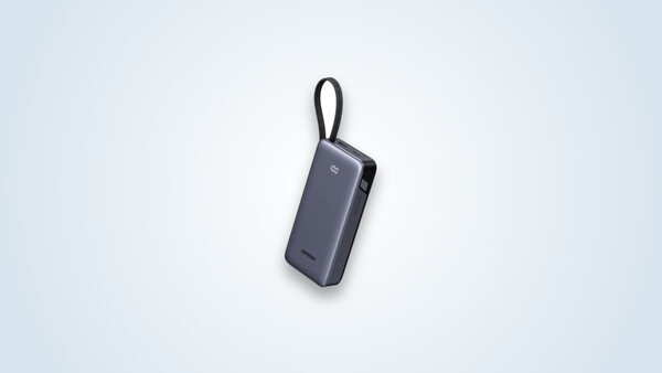 Ugreen Nexode 45W power bank held by its integrated USB-C cable, display showing 100% charge