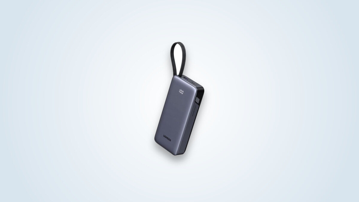 Ugreen Nexode 45W power bank held by its integrated USB-C cable, display showing 100% charge