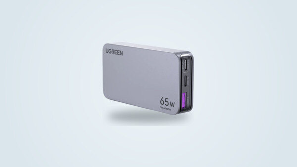 Ugreen Nexode Pro 65W Slim wall charger seen from a three-quarter angle, flat light grey case with two USB-C ports and one USB-A port visible on the edge