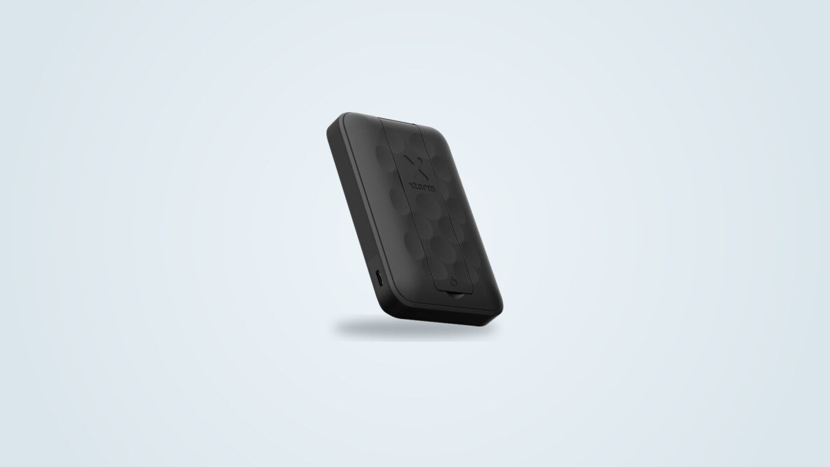 Power bank magnético Xtorm FS5W101 visto de tres cuartos, motivo de panal negro y logo de Xtorm visibles, soporte plegado bajo la carcasa