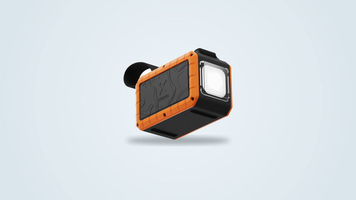 Externe Batterie Xtorm XR204 in Schwarz und Orange, Tragriemen und eingebaute Taschenlampe sichtbar, vor hellem Verlaufshintergrund