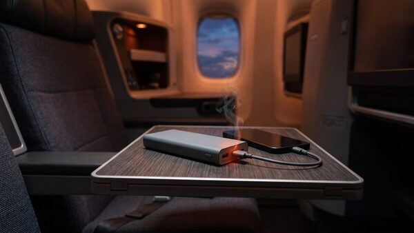 Power bank appoggiato sul tavolino di un aereo con un lieve bagliore arancione che suggerisce un rischio di surriscaldamento